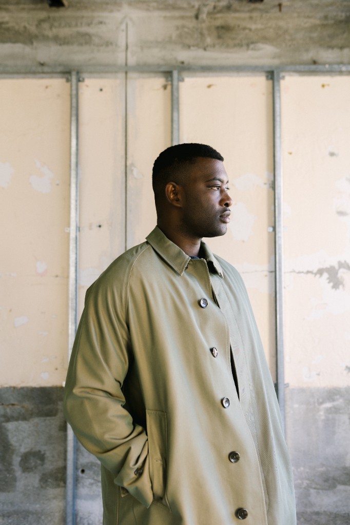 Joshua French, founder of Licorice Locker, in profile wearing a trench coat in an architectural build-out space.